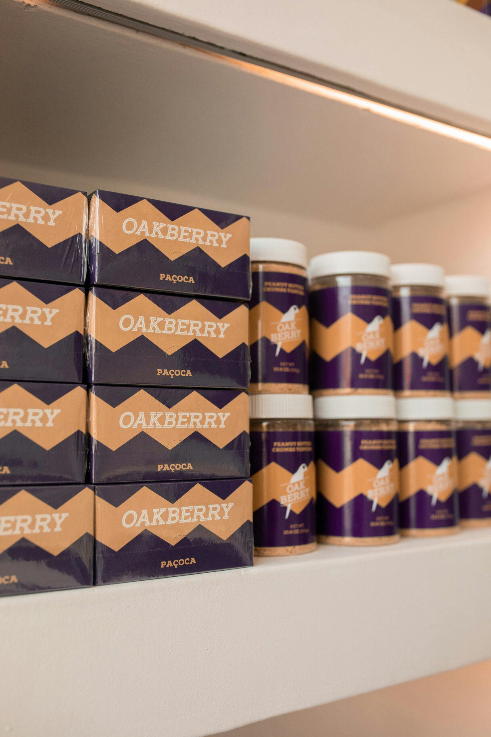 A shelf with boxes of OAKBERRY PB and OAKBERRY Paçoca