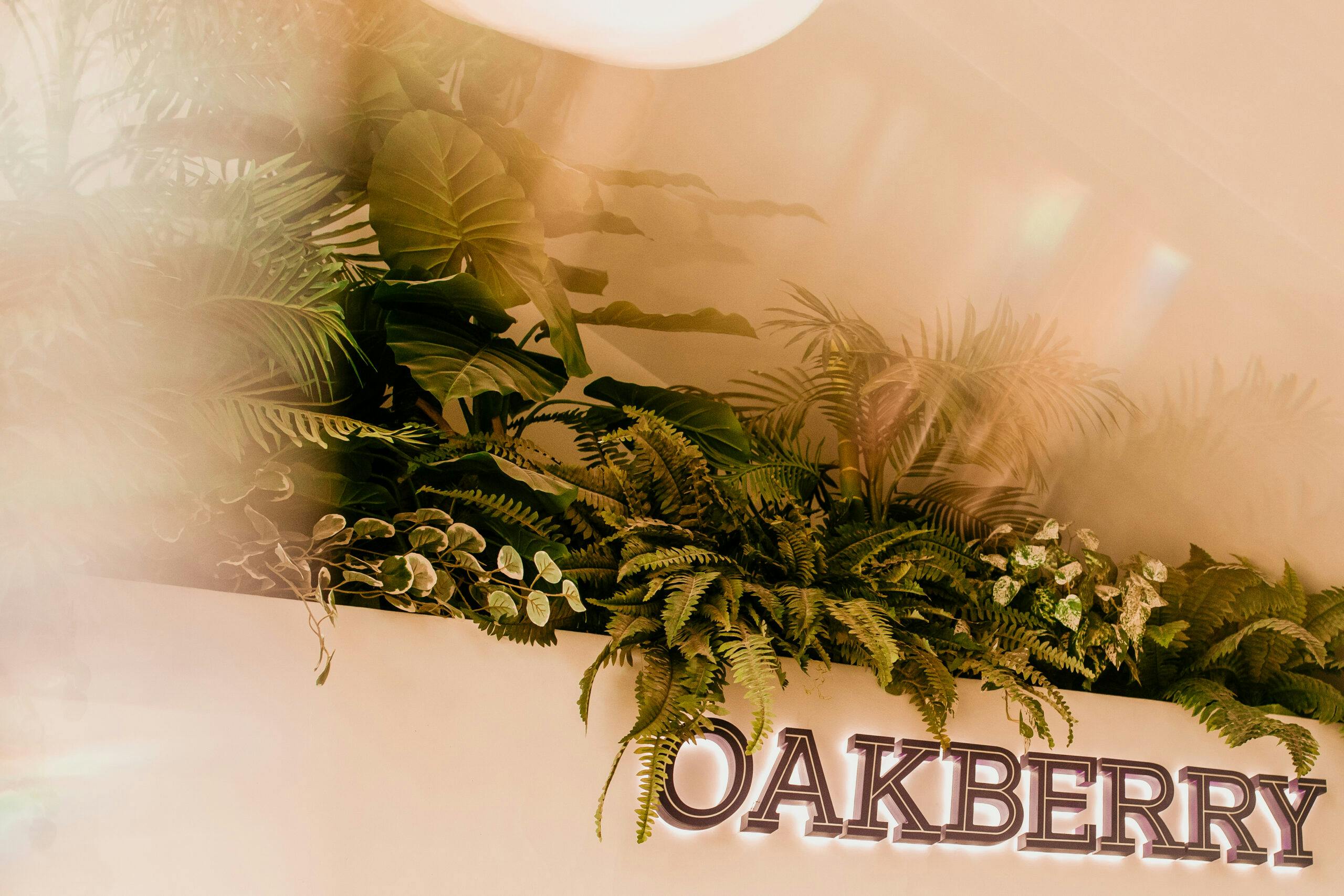 An OAKBERRY sign with plants on it
